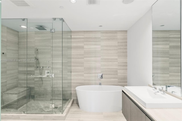 bathroom featuring tile walls, tile floors, separate shower and tub, and vanity