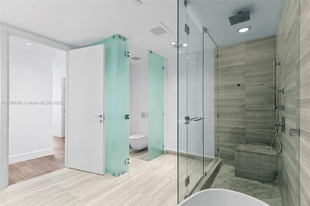 bathroom featuring wood finished floors, visible vents, a shower stall, and recessed lighting