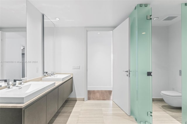 bathroom with dual bowl vanity, hardwood / wood-style flooring, and toilet