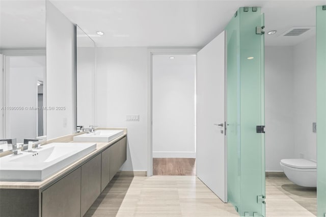 bathroom with double vanity, a sink, wood finished floors, and visible vents