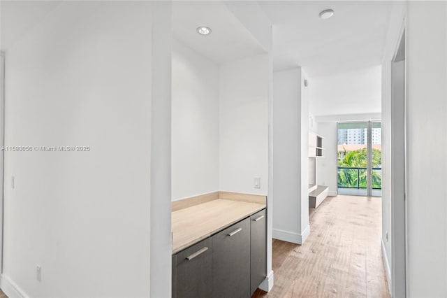 corridor with light wood-style flooring and baseboards