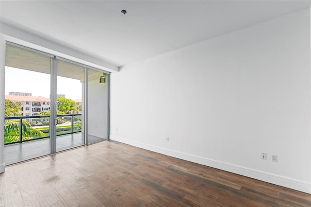 unfurnished room featuring hardwood / wood-style flooring and a wall of windows