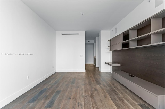 unfurnished living room featuring dark wood-type flooring, visible vents, and baseboards