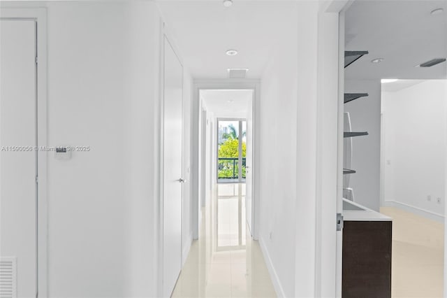 hallway featuring baseboards, visible vents, and light tile patterned floors