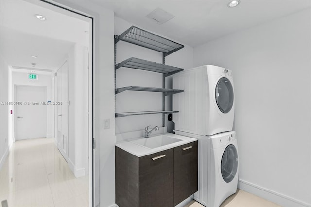 laundry room featuring recessed lighting, laundry area, stacked washer / dryer, a sink, and baseboards