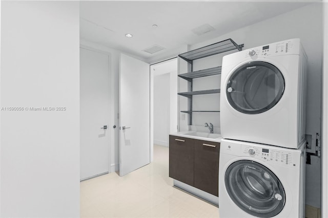 washroom with stacked washer / dryer, cabinet space, and a sink