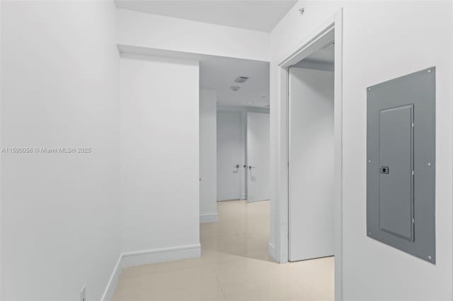 hall featuring electric panel, tile patterned floors, and baseboards