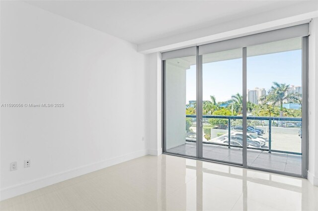 tiled spare room with a wall of windows and baseboards