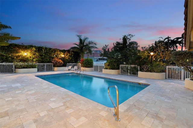 pool at dusk with a patio area