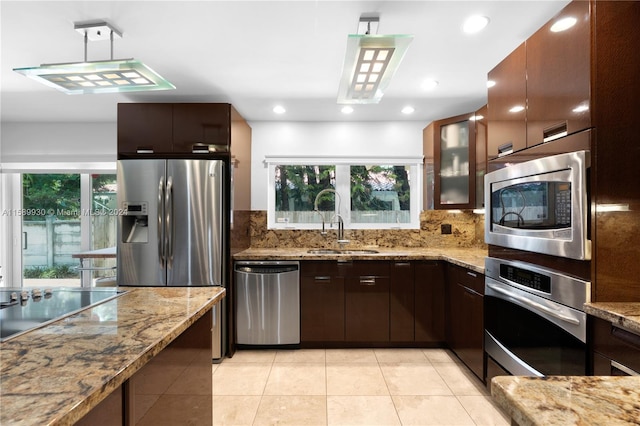 kitchen with stainless steel appliances, light stone countertops, and sink