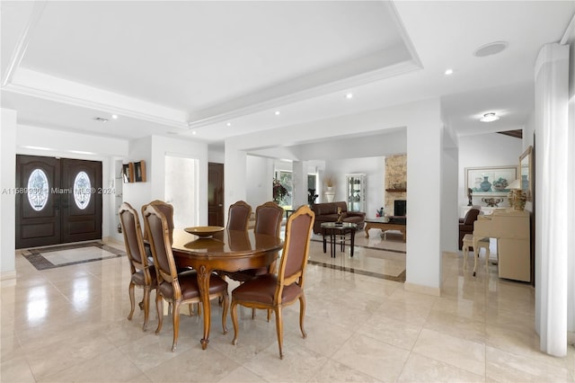 dining space featuring a fireplace, a tray ceiling, and a wealth of natural light