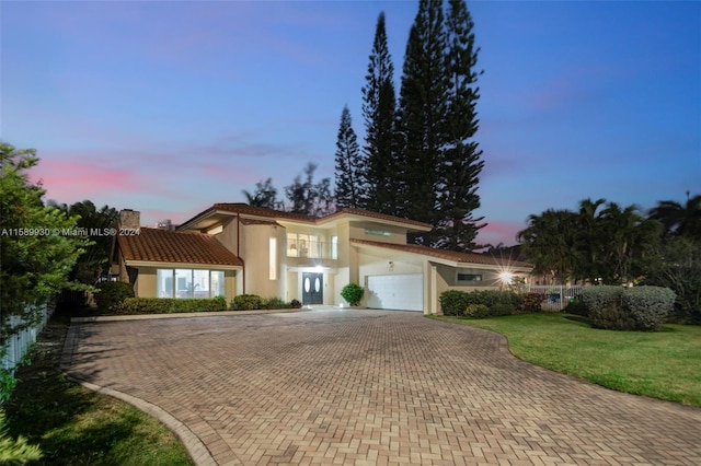 mediterranean / spanish-style house featuring a garage and a yard