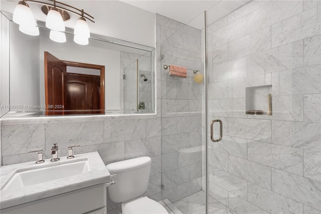 bathroom with vanity, a shower with shower door, tile walls, and toilet