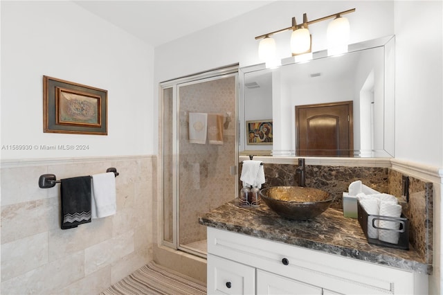 bathroom featuring vanity, a shower with door, and tile walls