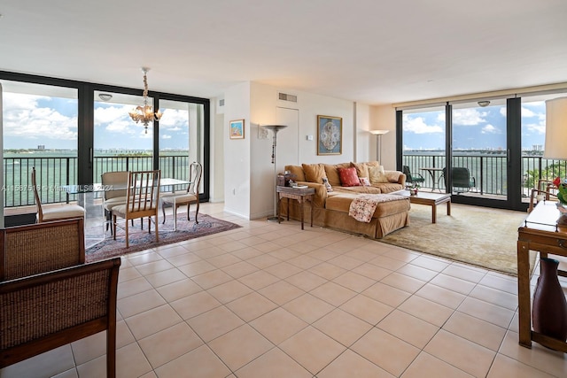 tiled living room featuring a water view, an inviting chandelier, and floor to ceiling windows