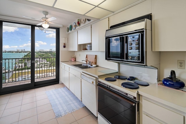 kitchen with white cabinetry, white appliances, light tile patterned flooring, a water view, and sink