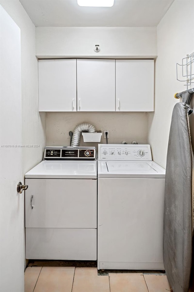 clothes washing area featuring cabinets, light tile patterned floors, and separate washer and dryer