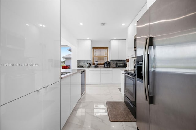 kitchen with appliances with stainless steel finishes, white cabinets, light tile patterned floors, and backsplash