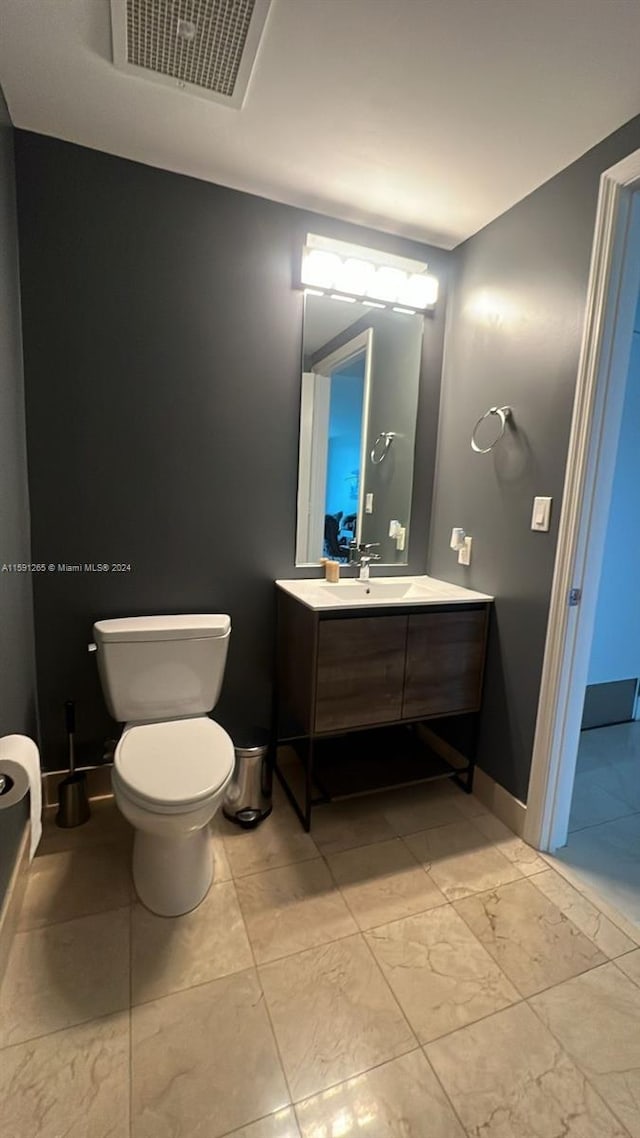 bathroom with tile flooring, toilet, and large vanity