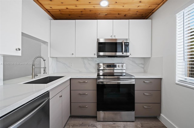 kitchen with appliances with stainless steel finishes, wooden ceiling, hardwood / wood-style floors, backsplash, and sink