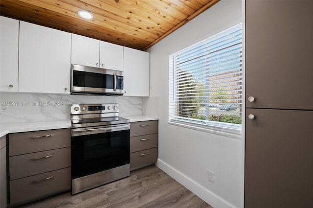 kitchen featuring stainless steel appliances, backsplash, white cabinetry, and wood-type flooring