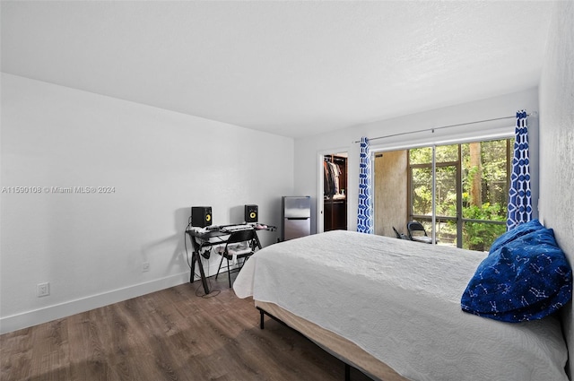 bedroom featuring a spacious closet, a closet, and dark wood-type flooring