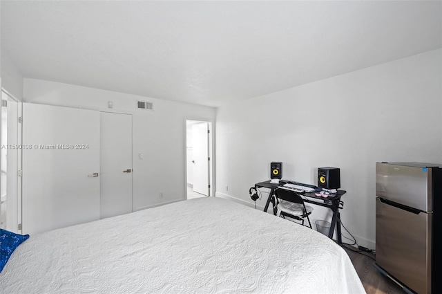 bedroom featuring dark hardwood / wood-style floors, a closet, and stainless steel refrigerator