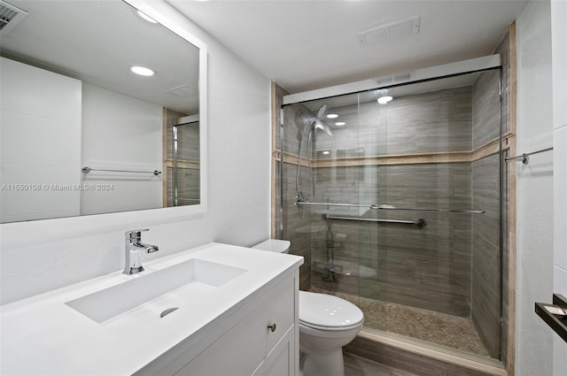 bathroom featuring walk in shower, wood-type flooring, vanity, and toilet