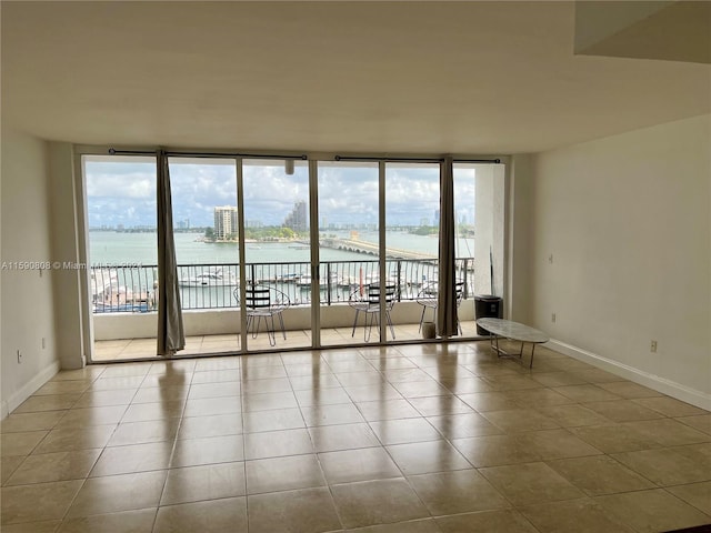 spare room featuring tile floors, expansive windows, and a water view