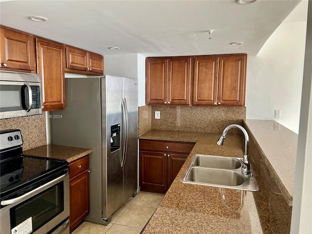 kitchen featuring stainless steel appliances, backsplash, sink, and light tile floors