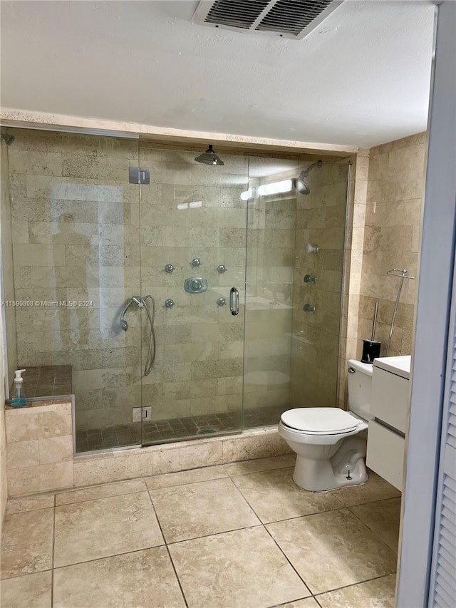 bathroom with tile flooring, vanity, toilet, and a shower with door