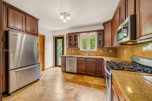 kitchen with light stone countertops, appliances with stainless steel finishes, sink, and backsplash