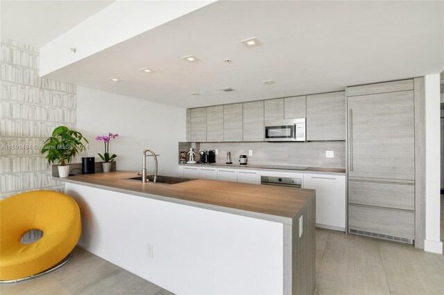 kitchen with kitchen peninsula, white cabinets, stainless steel appliances, and sink