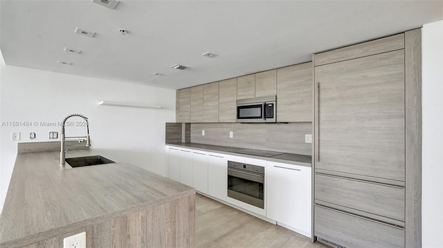 kitchen featuring light brown cabinetry, sink, light hardwood / wood-style flooring, and stainless steel appliances