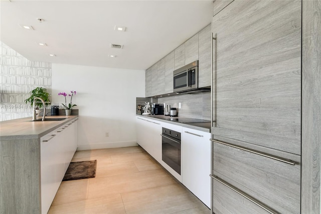 kitchen featuring sink, white cabinets, stainless steel appliances, and tasteful backsplash