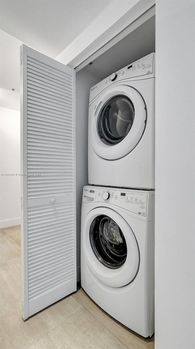 laundry area featuring stacked washing maching and dryer and light tile patterned floors