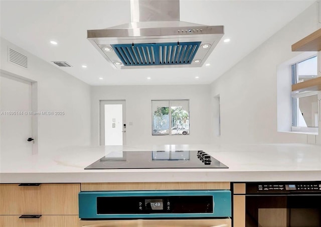 kitchen with black electric stovetop, wall oven, light brown cabinetry, and island range hood