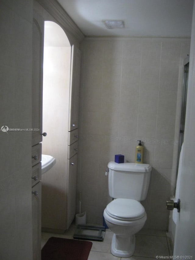 bathroom with tile floors, toilet, and tile walls