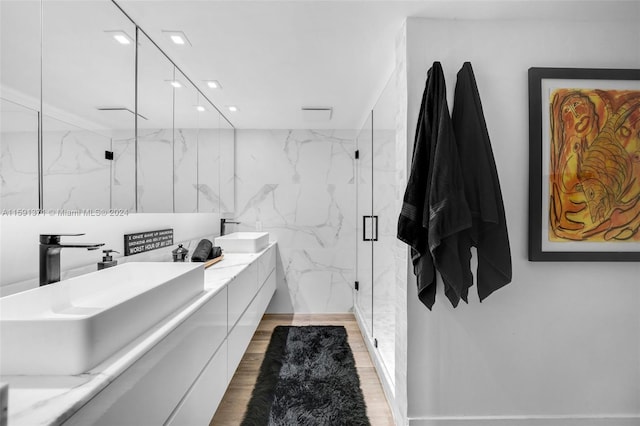 bathroom with walk in shower, wood-type flooring, oversized vanity, and double sink