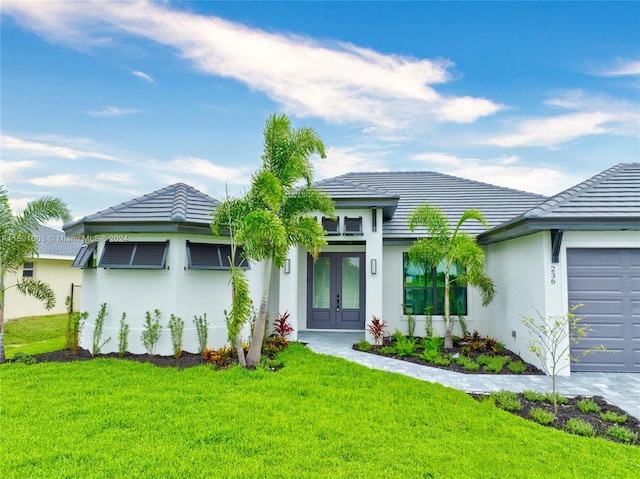 view of front of property with french doors, a garage, and a front lawn