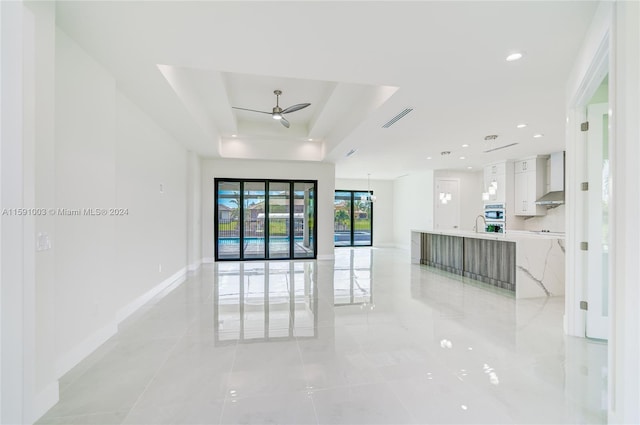 interior space featuring ceiling fan, a raised ceiling, sink, and light tile patterned flooring