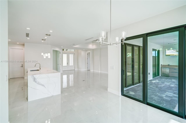 spare room with a notable chandelier, sink, french doors, and light tile patterned floors