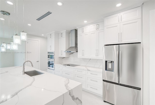 kitchen with stainless steel appliances, sink, backsplash, decorative light fixtures, and wall chimney range hood