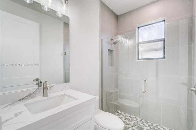 bathroom featuring vanity, a shower with door, and toilet