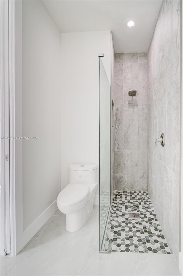 bathroom featuring toilet, tile patterned floors, and a tile shower