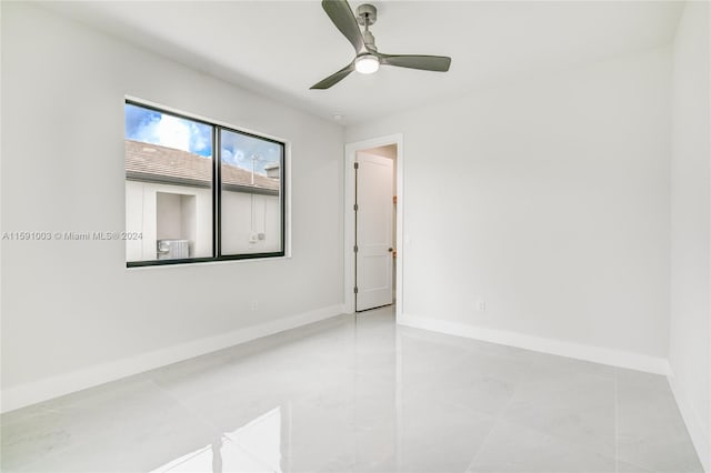 tiled spare room with ceiling fan