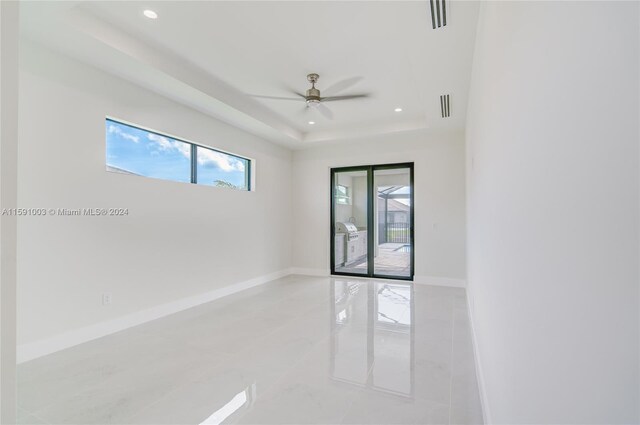 unfurnished room featuring tile patterned floors, ceiling fan, and a raised ceiling