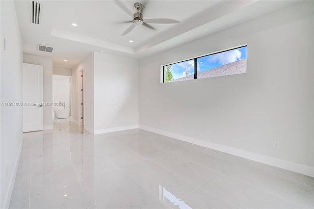 tiled spare room featuring ceiling fan and a raised ceiling