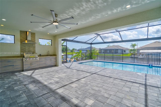 view of swimming pool with ceiling fan, glass enclosure, a patio, exterior kitchen, and grilling area