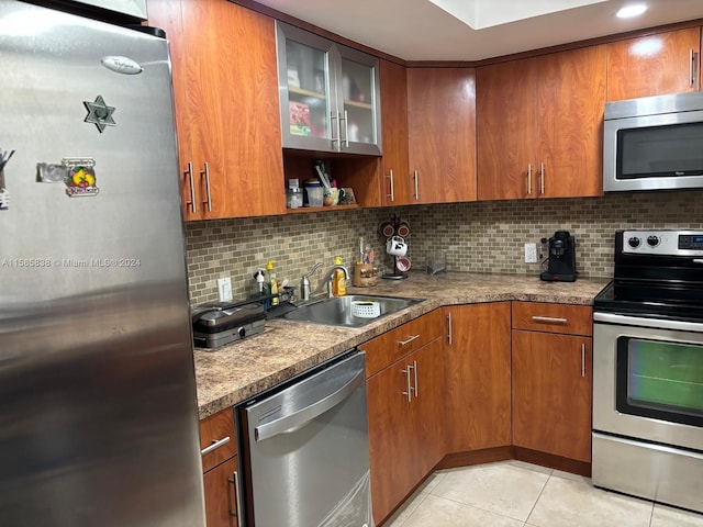 kitchen featuring appliances with stainless steel finishes, backsplash, light tile patterned floors, and sink